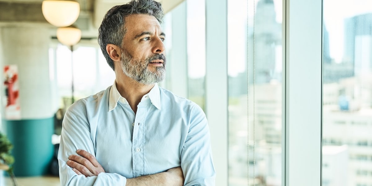 man in office looking out a window