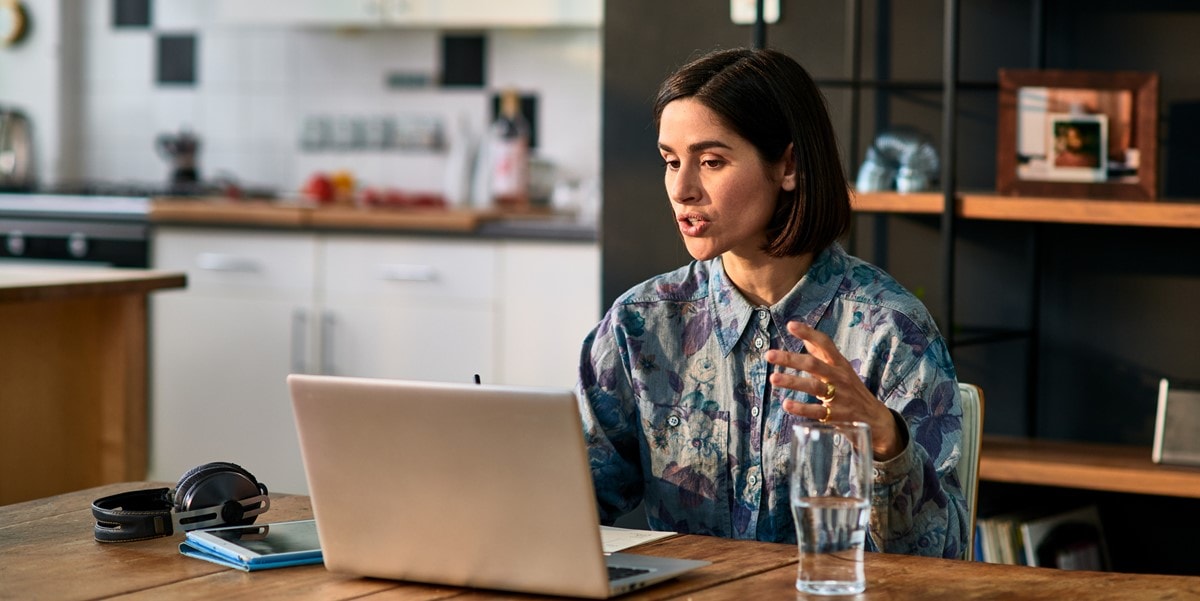 woman working at desk from home, in virtual meeting