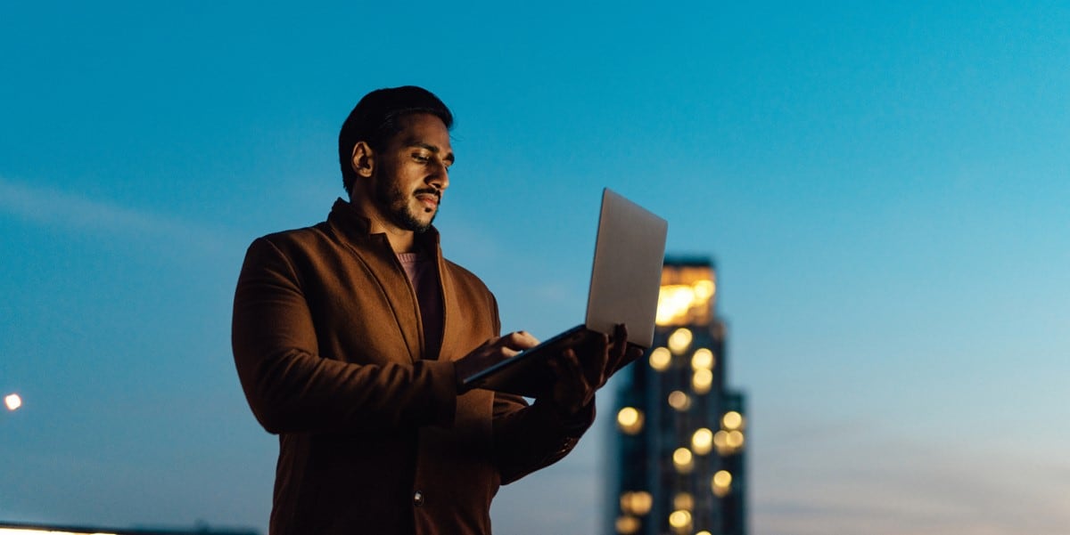 man standing outside holding laptop