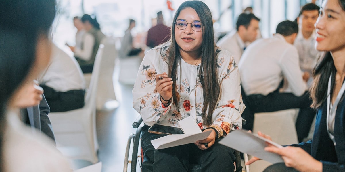 woman in a wheelchair in discussion with group of people